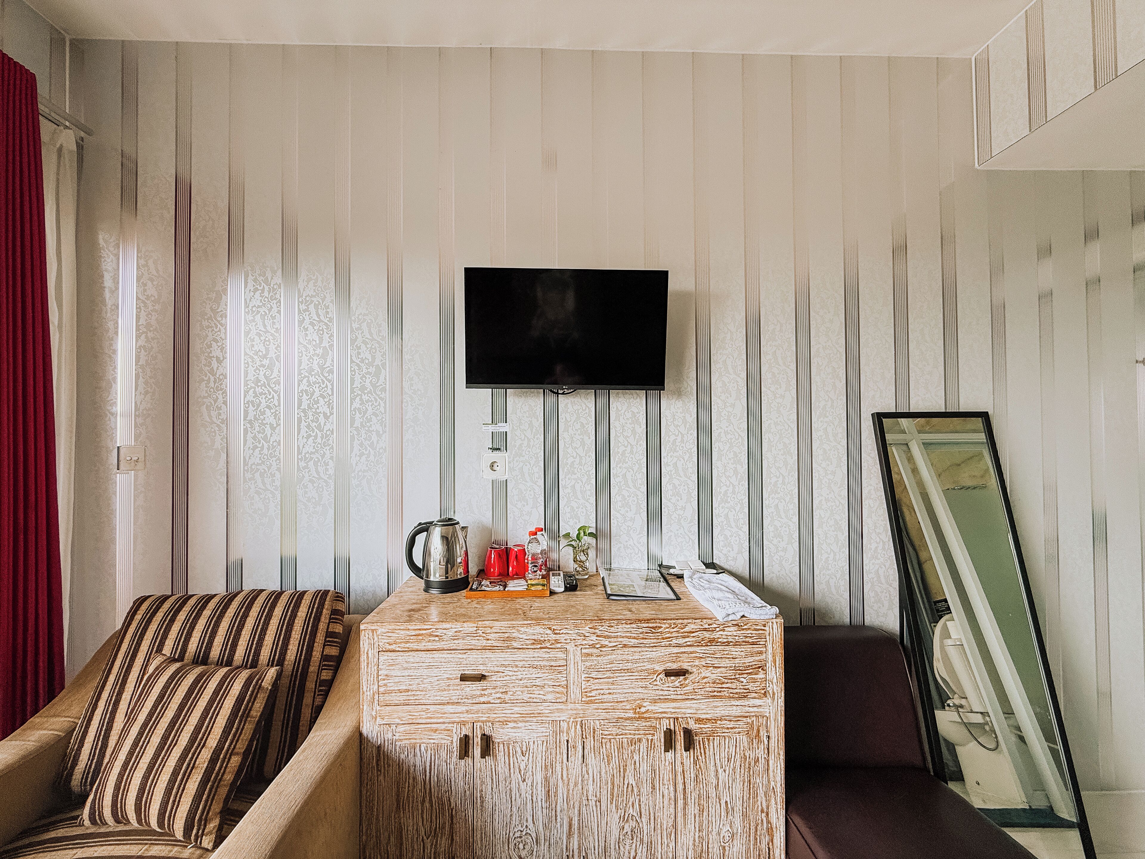 Una sala de estar con sofá, mesa de centro, televisor y espejo.