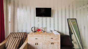 Una sala de estar con sofá, mesa de centro, televisor y espejo.