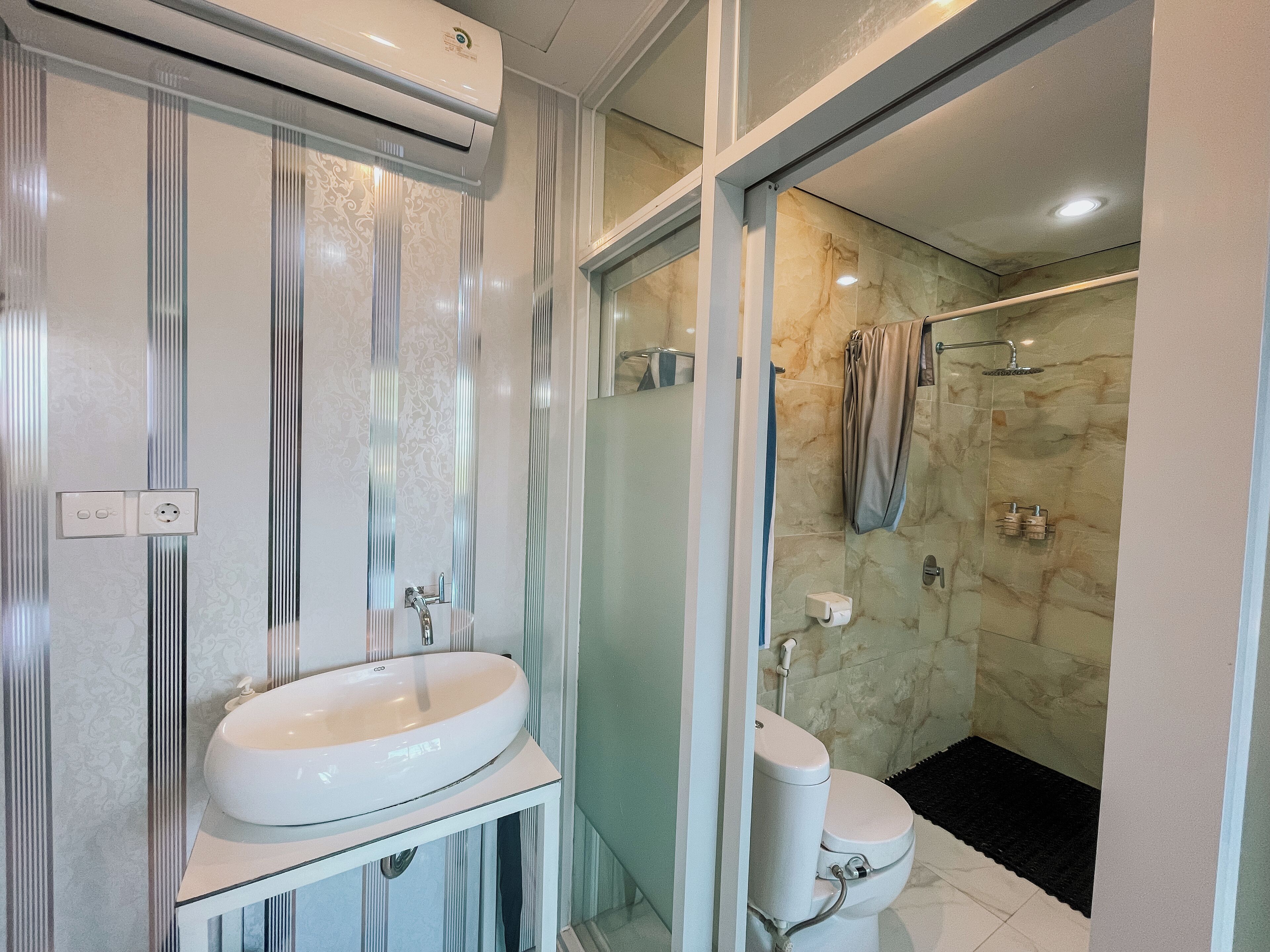 A bathroom with a glass shower enclosure, a white sink, and a toilet.