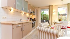 Eine moderne Küche mit integrierten Geräten, einem gestreiften Sofa und einem Essbereich mit Tisch und Stühlen.