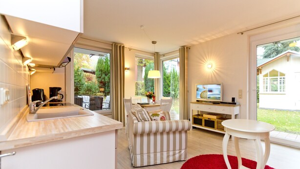 Eine moderne Küche mit integriertem Spülbecken, einem Essbereich mit einem gestreiften Sofa und einem kleinen weißen Tisch.