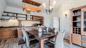 Una cocina moderna con armarios de madera, una mesa de comedor con sillas, una araña y una pared de piedra.