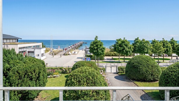 Une vue sur la côte, avec une jetée, un bâtiment portant l’inscription « NIGEL DES BREESE », et une végétation bien entretenue.
