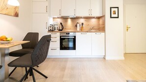 A modern kitchen with white cabinets, a black oven, and a wooden countertop. - Villa Medici Heringsdorf, App. 02 (Heringsdorf)