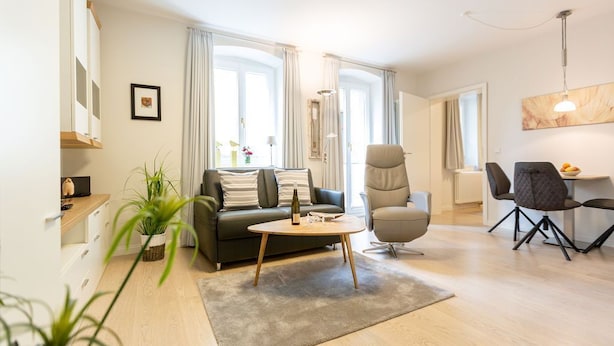 A modern living room with a sofa, armchair, coffee table, and dining area. - Villa Medici Heringsdorf, App. 02 (Heringsdorf)