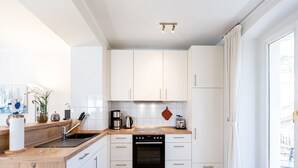 A modern kitchen with white cabinets, a wooden countertop, and a built-in oven.