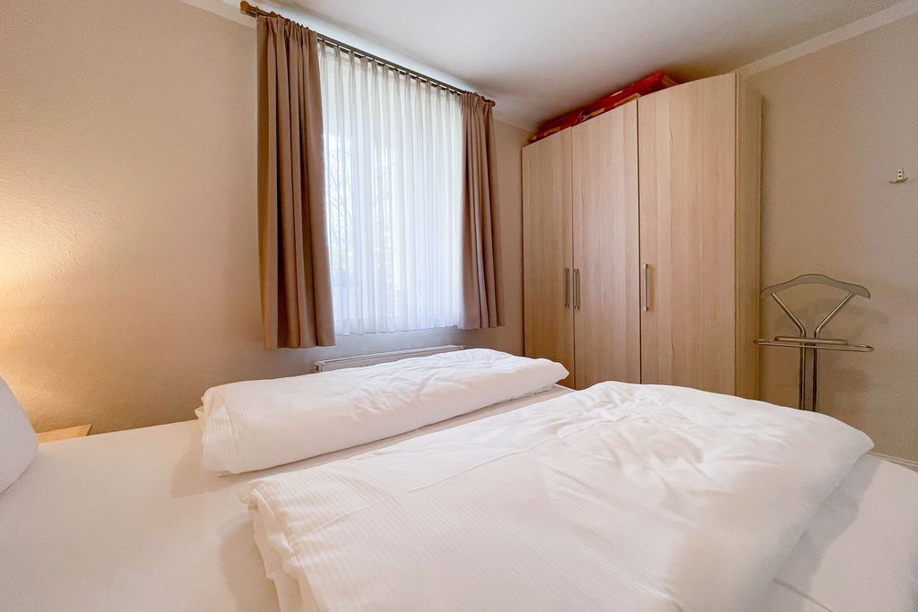 A hotel room with two beds, a wardrobe, and a window with curtains.