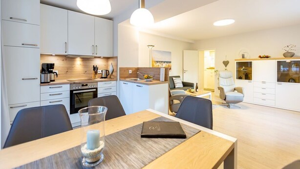 A modern kitchen with white cabinets, a wooden countertop, and pendant lighting. - Villa Medici Heringsdorf, apt. 01 (Heringsdorf)