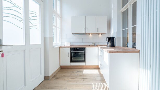 A modern kitchen with white cabinets, a built-in oven, and a wooden countertop. - Villa Hartmann-Drewitz, App. 03 (Heringsdorf)