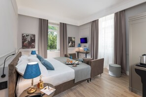 A modern hotel room with a large bed, a desk, a TV, and a view of greenery outside. - Hotel La Ville Rome (Rome)