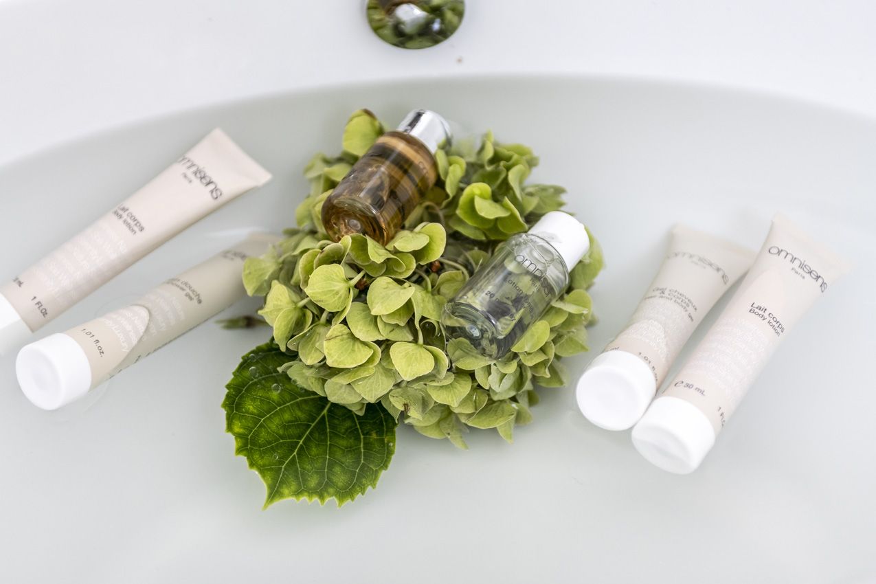 A white sink with four tubes of body lotion and a small bottle of oil.