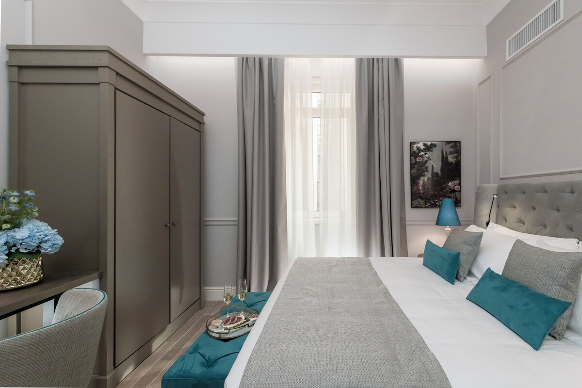 A bedroom with a bed, a nightstand, a lamp, and a window with curtains.
