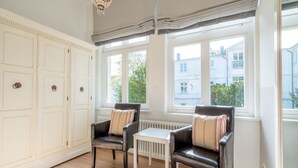 A room with two leather chairs, a small white table, and large windows offering a view of a building outside. - Villa Hartmann-Drewitz, App. 06 (Heringsdorf)