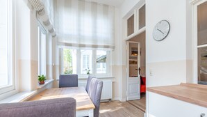 A bright room with a wooden table, chairs, a radiator, and a clock on the wall. - Villa Hartmann-Drewitz, App. 06 (Heringsdorf)