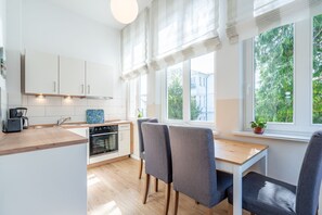 Eine moderne Küche mit weißen Schränken, einer Holz Arbeitsplatte und einem Essbereich mit grauen Stühlen.