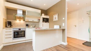 A modern kitchen with white cabinetry, a built-in oven, a microwave, and a coffee machine.