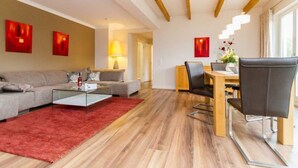 A modern living room with a sofa, a coffee table, and a dining area with chairs and a table.