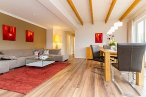 Un salon moderne comprenant un canapé, une table basse et un coin repas avec des chaises et une table.