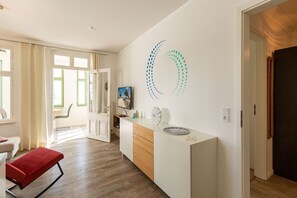 Ein modernes Wohnzimmer mit einer roten Bank, einer weißen Kommode und einem Wandbild.