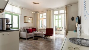 En moderne stue med en sofa, en rød lænestol og et spiseområde med et bord.