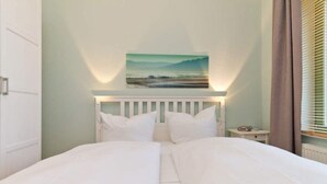A double bed with white bedding, a headboard, and a painting above it. - Villa Frohsinn, app. 06 (Heringsdorf)