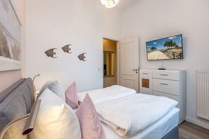 Un dormitorio con cama, televisor, cómoda y decoración en la pared.