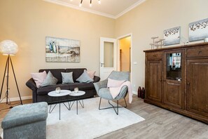 Una sala de estar con sofá, sillones, una mesa de centro, una lámpara de pie y un aparador.
