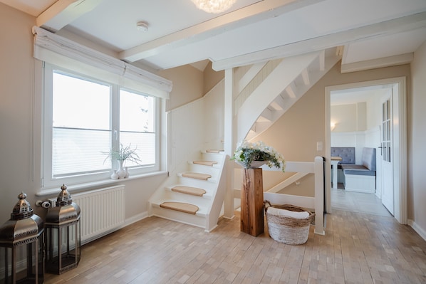 Een trap met houten treden en een witte leuning, die leidt naar een plateau met een plant en een mand.