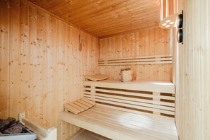 Een houten sauna met banken en een emmer.