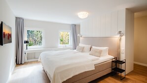 Ein modernes Schlafzimmer mit einem großen Bett, einem Nachttisch, einem Heizkörper und einem Fenster mit Vorhängen.