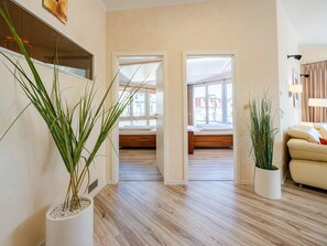 Una sala de estar moderna con suelo de madera, un sofá y dos plantas en macetas.