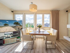 Uma sala de estar moderna com uma mesa de jantar, duas cadeiras, uma televisão e uma estante.