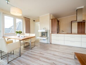 Een moderne keuken met een houten aanrecht, witte kastjes en een zithoek met een tafel en stoelen.