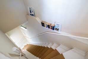 A staircase with a handrail, a wall-mounted bookcase with books, and a framed picture. - Villa Schlossbauer, App. 06 Remise (Heringsdorf)