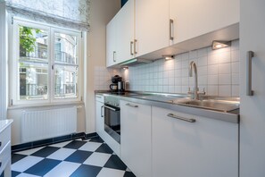 A modern kitchen with white cabinets, a stainless steel sink, and a black and white checkered floor. - Villa Schlossbauer, App. 06 Remise (Heringsdorf)