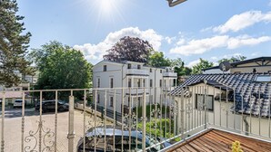 A residential area with a balcony, a parked car, and a house with a tiled roof. - Villa Schlossbauer, App. 06 Remise (Heringsdorf)