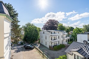 A residential building with a paved driveway, parked cars, and a large tree. - Villa Schlossbauer, App. 06 Remise (Heringsdorf)