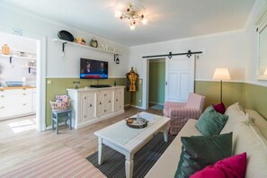 Un salon confortable avec une télévision, un canapé, une table basse et un coin repas avec un comptoir de cuisine.