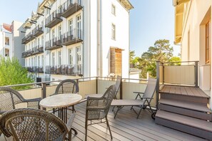 Un balcon avec des meubles en osier, une petite table et un chien.