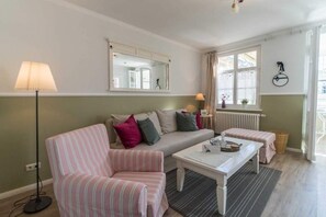 Un salon chaleureux avec un canapé à rayures, une table basse blanche et un lampadaire.