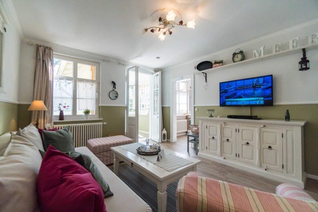 Una sala de estar con un sofá, un sillón a rayas, una mesa de centro, un televisor y un aparador.
