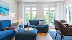 Una sala de estar moderna con un sofá azul, un reposapiés y un comedor con sillas y una mesa.
