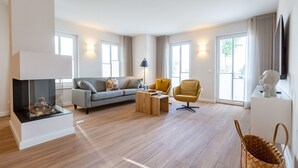 Un salon spacieux comprenant un canapé, des fauteuils, une table basse et une cheminée.