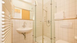 A modern bathroom with a glass-enclosed shower, a sink, and a toilet. - Villa Astrid, T6 Stralsund (Heringsdorf)