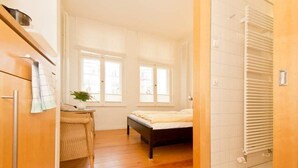 A bedroom with a bed, a chair, a small table, and a window. - Villa Astrid, T6 Stralsund (Heringsdorf)