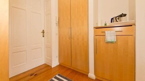 A hallway with a wooden wardrobe, a white door, and a small kitchen area with a sink and a towel hanging on the door. - Villa Astrid, T6 Stralsund (Heringsdorf)