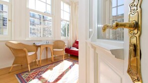 Ein Zimmer mit einem großen Fenster, einem gemusterten Teppich und einem Messing-Türgriff.