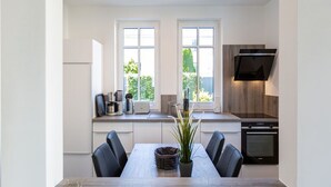 Een moderne keuken met witte kasten, een inbouwoven en een groot raam.