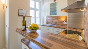 Una cucina moderna con bancone in legno, una bottiglia di vino e una ciotola di frutta.