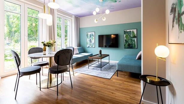 Ein modernes Wohnzimmer mit Essbereich, großen Fenstern und Wandgemälde an der Decke.